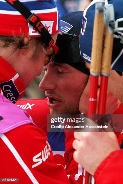 An exhausted Petter Northug of Norway is congratulated by team members after winning the Gold medal during the Men's Cross Country 50KM Race at the...