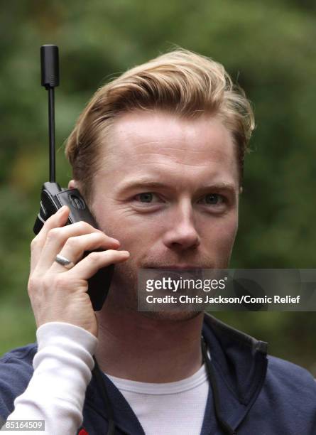 Ronan Keating speaks to his family on sat phone as he takes a rest during trekking on the on the first day of The BT Red Nose Climb of Kilimanjaro on...