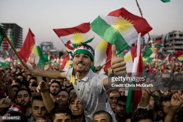 Supporters wave flags and chant slogans inside the Erbil Stadium while waiting to hear Kurdish President Masoud Barzani speak during a rally for the...