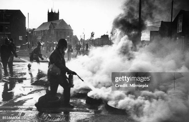 Toxteth Riot, 5th July 1981: Police officers armed with fire extinguisher attempt to tackle a road block of burning tyres during the Toxteth riots.