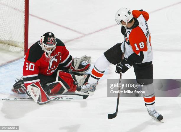 Goaltender Martin Brodeur of the New Jersey Devils makes a pad save as Mike Richards of the Philadelphia Flyers looks for the rebound. Brodeur...