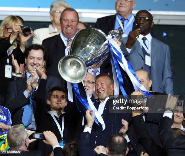 Chelsea FC owner Roman Abramovich lifts the trophy in celebration while Chancellor of the Exchequer George Osborne applauds after their victory in...