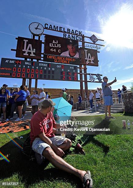 Fans sit under the center field score board during a spring training game of the Los Angeles Dodgers home opener against Chicago White Sox at...