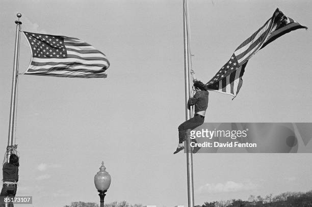 Unidentified demonstrators climb flagpoles to remove the American flag during a massive rally demonstration in opposition to the war in Vietnam and...