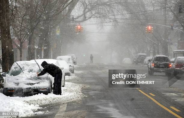 Man cleans the snow from his car March 2, 2009 in the Bronx Borough of New York City. Heavy snows created choas around the northeast United States....