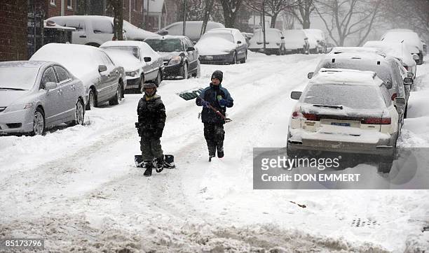 Young snow shovelers walk down a snowy street March 2, 2009 in the Bronx Borough of New York City. Heavy snows created choas around the northeast...