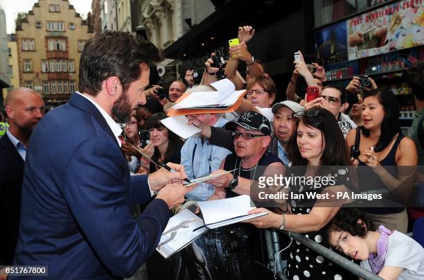 Hugh Jackman signs autographs for fans whilst arriving for the UK Premiere of The Wolverine, at the Empire Leicester Square, London.