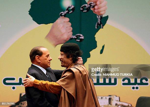 Libyan leader Moamer Kadhafi embraces Italian Prime Minister Silvio Berlusconi during a meeting in Sirte, 600 kms east of Tripoli, on March 2, 2009....