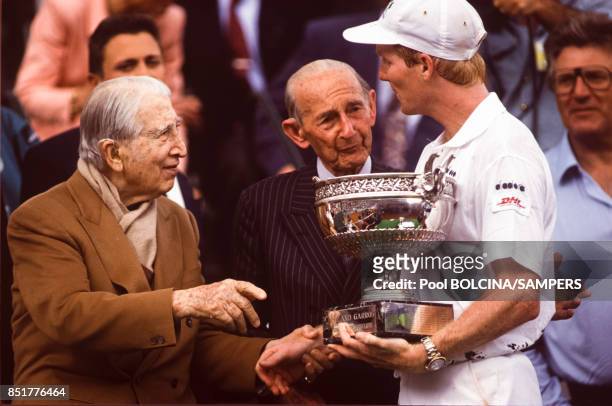 Le vainqueur Jim Courier reçoit le saladier des mains des vétérans René Lacoste et Henri Cochet lors des Internationaux de France de tennis au stade...