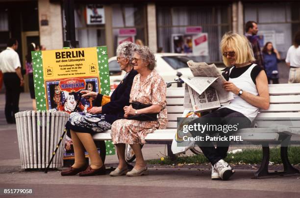 Deux femmes âgées assises sur un banc à côté d'un homme lisant son journal en juillet 1991 à Berlin, Allemagne.