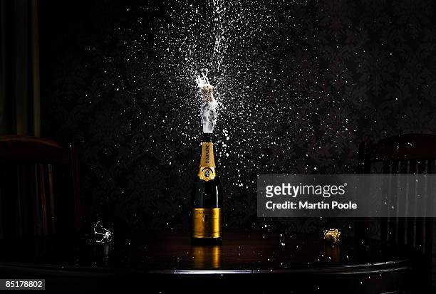 bottle of champange on table exploding cork - champagne stock-fotos und bilder