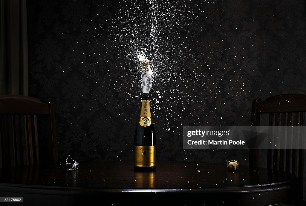 Bottle of champange on table exploding cork