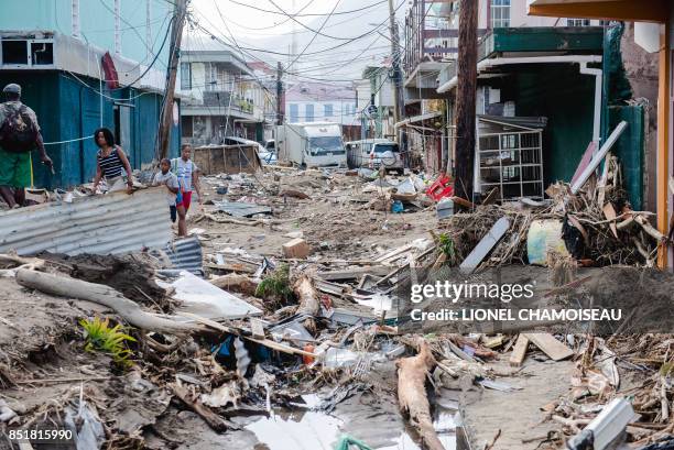 Residents stand amid rubble September 22, 2017 in Roseau, capital of the Caribbean island Dominica, four days after the passage of Hurricane Maria....