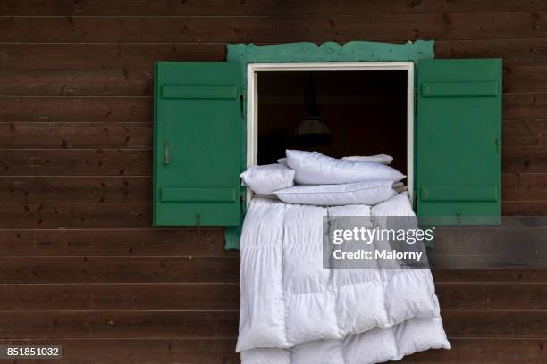 duvet airing on the ledge of an open green window of a log cabin - bedclothes stock-fotos und bilder