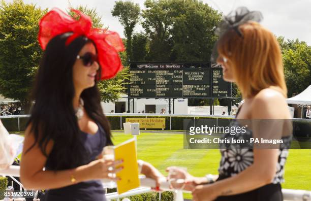 Two ladies study the race card on day four of Glorious Goodwood at Goodwood Racecourse, Chichester.