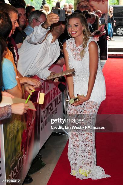 Margot Robbie poses for a photograph with a fan after arriving for the world premiere of About Time, at Somerset House, London.