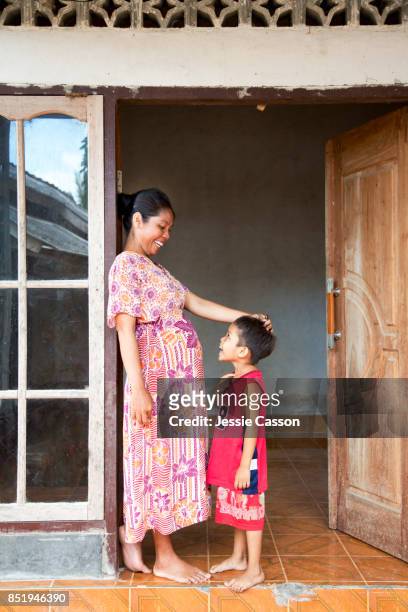 pregnant mother interacts with son in house doorway - indonesia family stock pictures, royalty-free photos & images