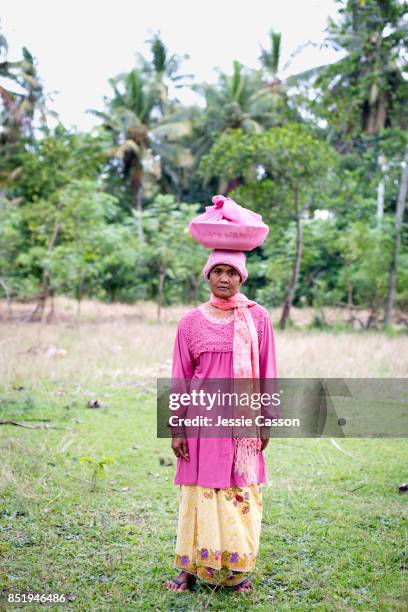 a woman ready to attend a wedding stands with food dish on her head - bali women tradition head stock pictures, royalty-free photos & images