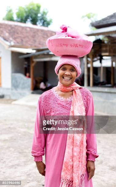 a woman ready to attend a wedding stands with food dish on her head - bali women tradition head stock pictures, royalty-free photos & images