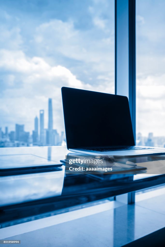 Desk with laptop in front of shanghai city skyline