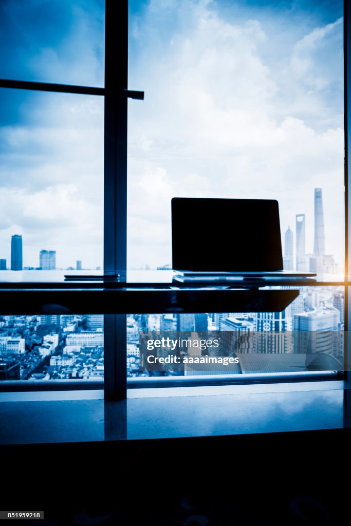 Desk with laptop in front of shanghai city skyline