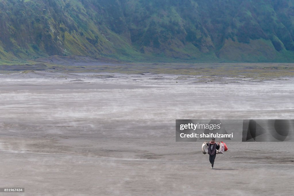 An unidentified local walking in sandstorm near Mount Batok at Bromo Tengger Semeru National Park