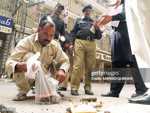 Plainclothed Pakistani security official collects hand grenades and packed ball-bearings carried by gunmen during an attack on a bus which was...