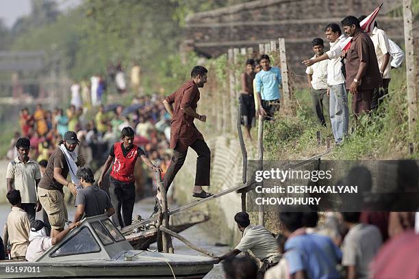 Indian Bollywood actor Abhishek Bachchan runs up a gangway plank as he returns from filming on the Ganga river at Agarpara, near Kolkata, on March 3,...