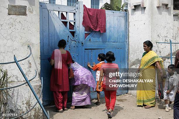 Curious onlookers take a peek through the entrance gate of a farmhouse where Indian Bollywood actress Aishwarya Rai and actor Abhishek Bachchan are...