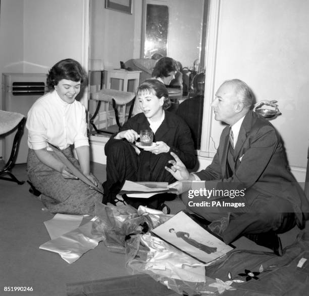 Costume designer and photographer Cecil Beaton sits on the floor with seamstress Jane Helder and American actress Julie Harris. A costume fitting was...