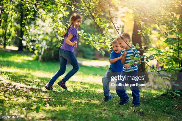 brothers and sister playing tag in garden - playing tag stock pictures, royalty-free photos & images