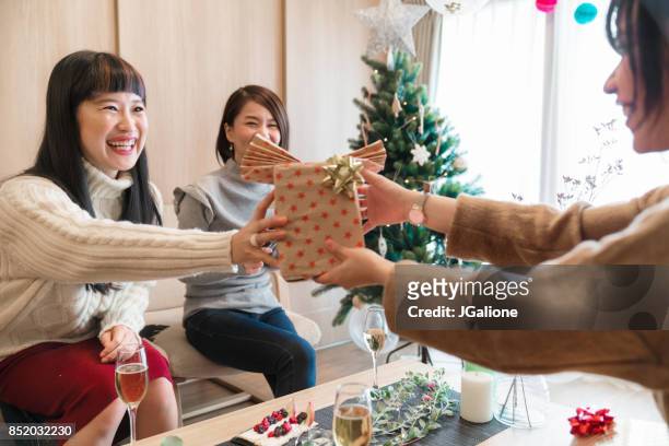 young female friends exchanging christmas presents - transfer stock pictures, royalty-free photos & images