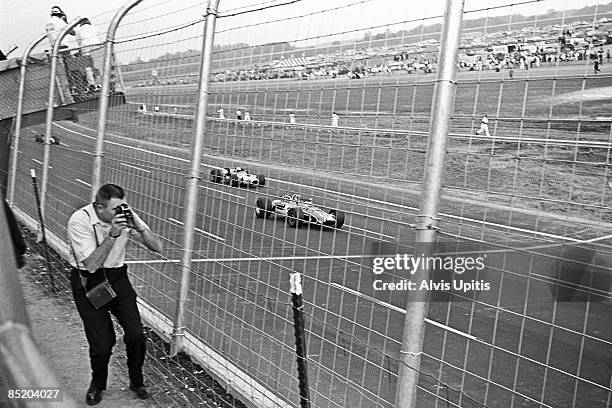 Bobby Unser driving an Eagle-turbo Offy competes as a fan films the Inaugural 250 Mile USAC race at Michigan International Speedway on October 13,...