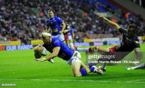 Leeds Rhinos Carl Ablett goes over for a try past Wigan Warriors Chris Tuson, during the Super League match at the DW Stadium, Wigan.