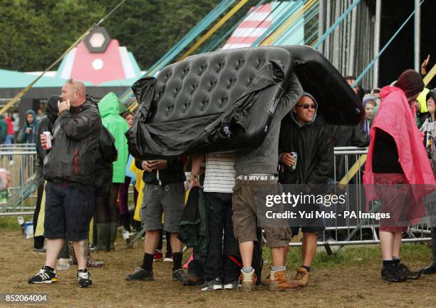 Festival goers shelter from the rain at Bestival, held at Robin Hill Country Park on the Isle of Wight.