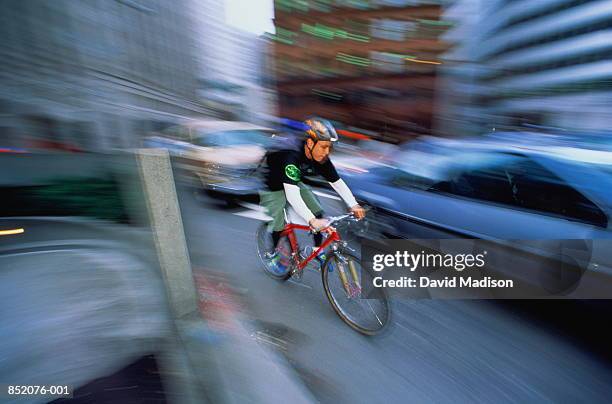 young bicycle messenger riding on urban street (blurred motion) - bike messenger stock pictures, royalty-free photos & images