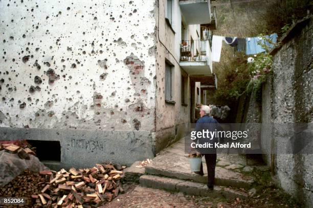 Resident walks passed a bullet-scarred apartment building November 16, 2000 in the war-damaged city of Srebrenica, Bosnia. This year marks the fifth...