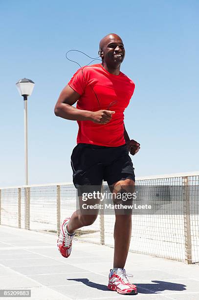 male jogging on promenade - african male red shirt stock-fotos und bilder