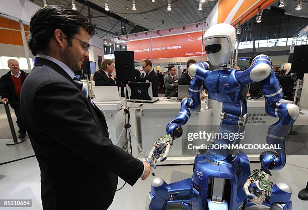 German robotics engineer Thomas Wimboeck shakes hands with the "mobile robotic system" Rollin' Justin at the world's biggest high-tech fair, the...