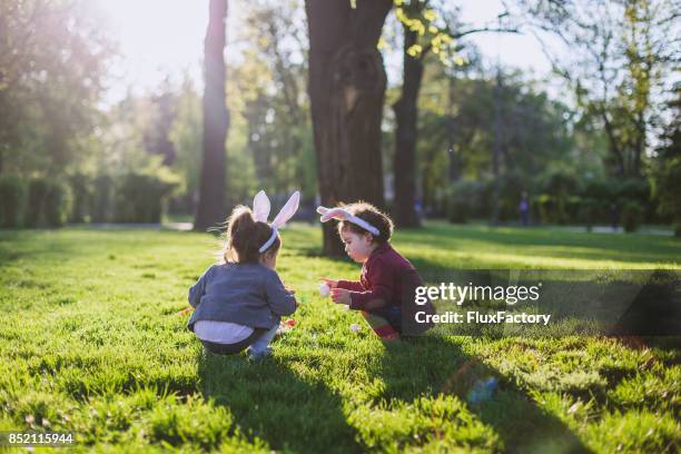 little girls playing on grass - easter egg hunt stock pictures, royalty-free photos & images