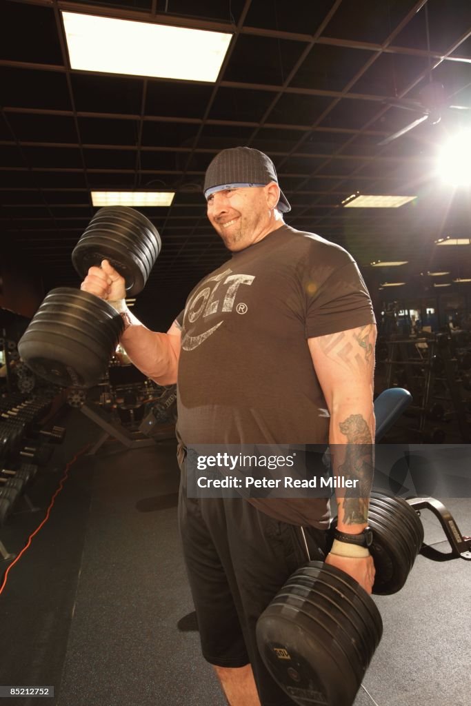 Portrait of former NFL player Tony Mandarich lifting weights at... News