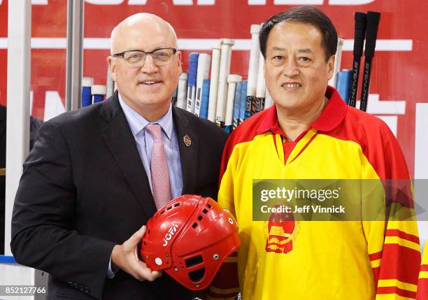 Deputy commissioner Bill Daly and 1981 Chinese Mens National team player Yin Jiwu hold a helmet being donated to the Hockey Hall of Fame during the...