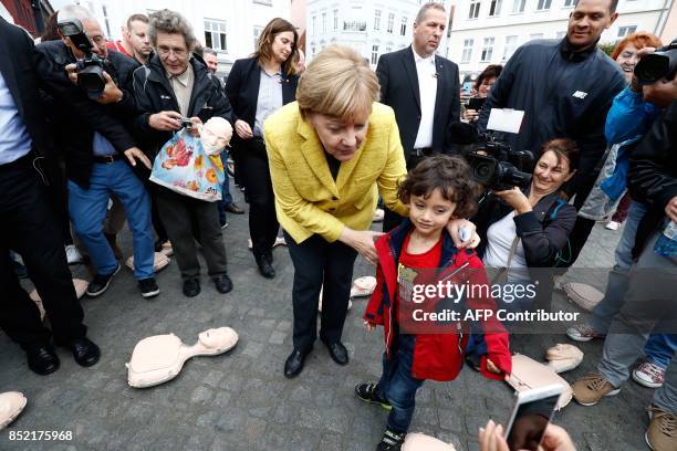 German Chancellor Angela Merkel poses for a picture with a child as she visits a booth of the German Red Cross staging an information campaign on...