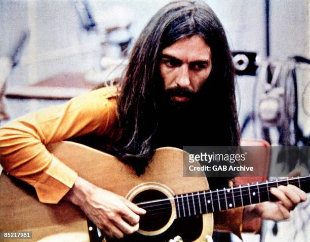 Photo of George HARRISON; playing acoustic guitar, c.1970/1971