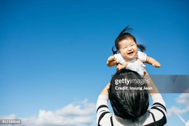 mother lifting young baby daughter in air - baby blue stock pictures, royalty-free photos & images