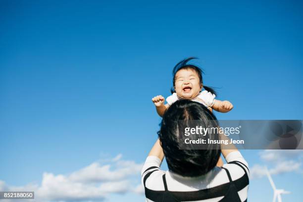 Mother lifting young baby daughter in air