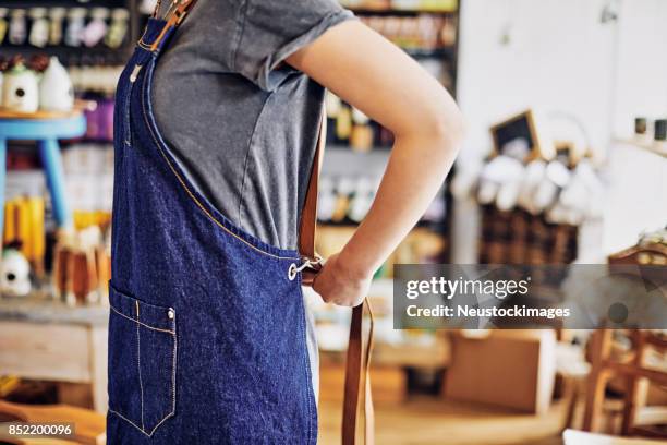 buik van jonge vrouwelijke eigenaar denim schort dragen in deli - apron stockfoto's en -beelden