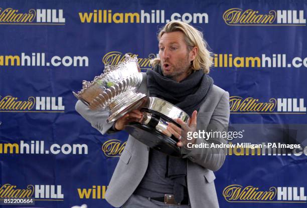 Robbie Savage almost drops the Kilkerran Cup before handing it out after the horse Hi There won The William Hill Download The App Handicap Stakes...