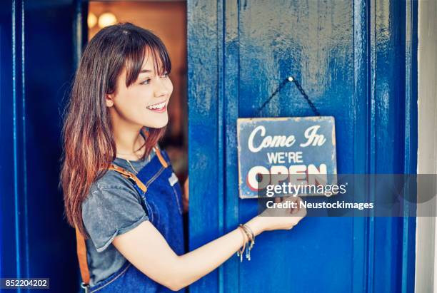 vrouwelijke ondernemer opknoping open aanlog deli deur glimlachend - open sign on door stockfoto's en -beelden