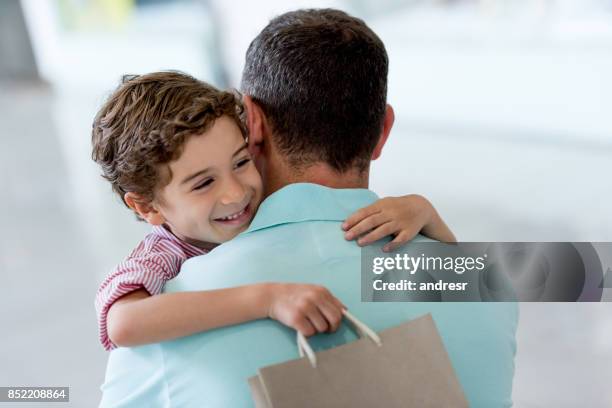 affectionate son hugging his father at the shopping center - father gift stock pictures, royalty-free photos & images